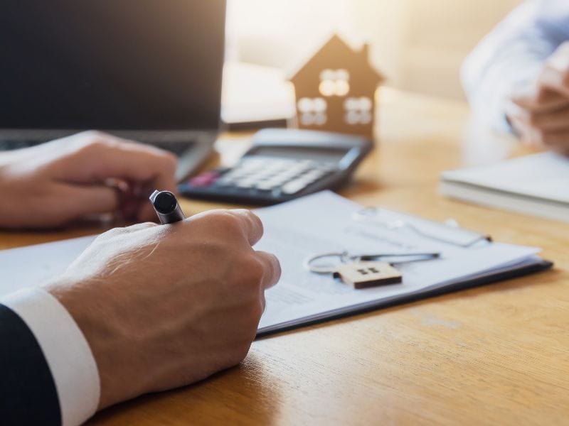 uomo firma un contratto a indicare che il miglior modo per vendere casa è contrattare