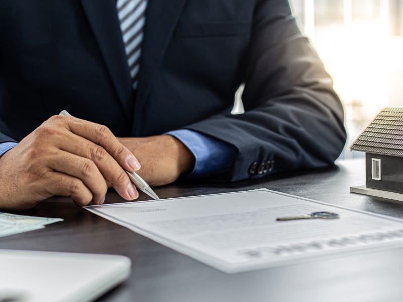 uomo con penna e contratto sopra il tavolo