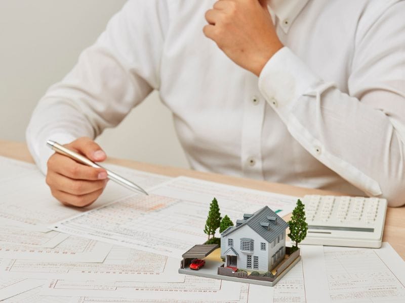 valutazione immobiliare uomo con carte e modellino di casa