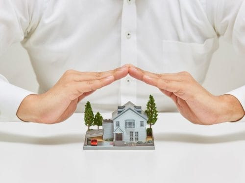 uomo protegge modellino di casa con le mani a simbolo di come tutelarsi nella vendita di un immobile