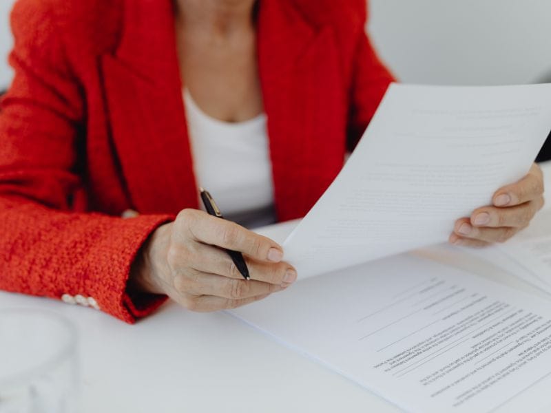 donna con penna in mano guarda dei documenti