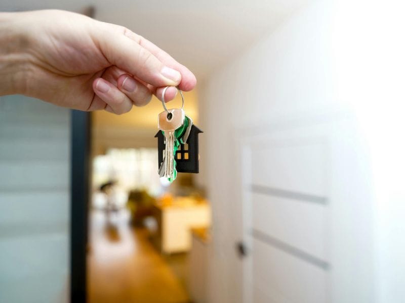 mano tiene in mano chiavi di casa davanti a porta aperta
