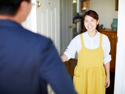 donna apre porta di casa a un possibile acquirente della sua casa in vendita