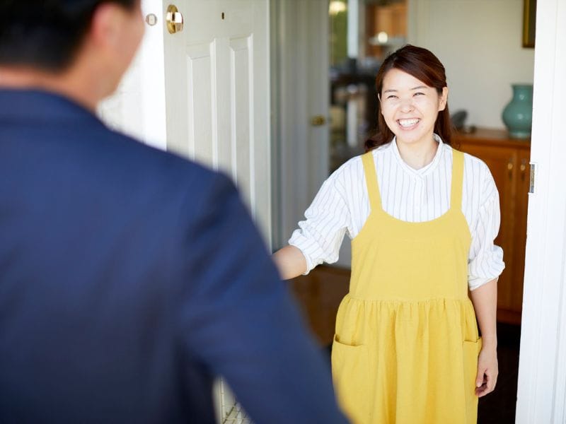 donna apre porta di casa a un possibile acquirente della sua casa in vendita