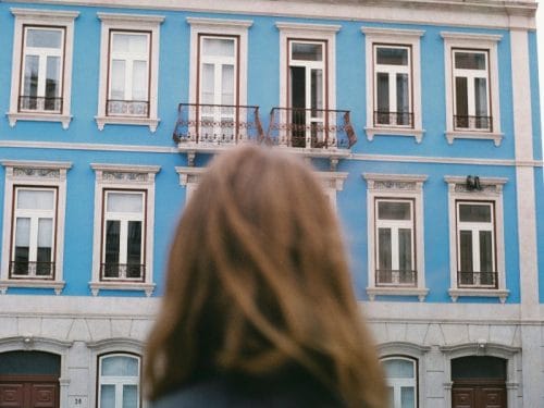 donna davanti a palazzina pensa a come scegliere la casa giusta da comprare