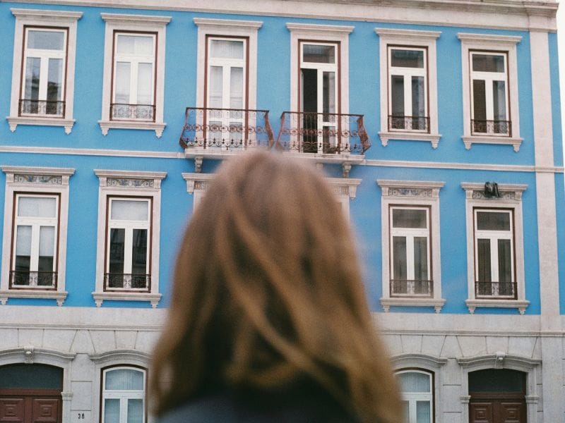 donna davanti a palazzina pensa a come scegliere la casa giusta da comprare
