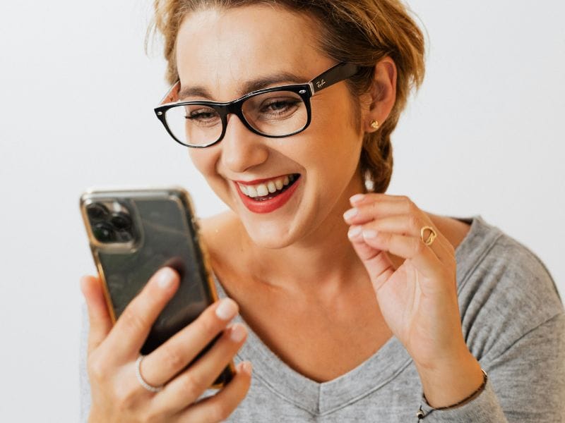 donna felice con smartphone per avere concluso la compravendita immobiliare con successo