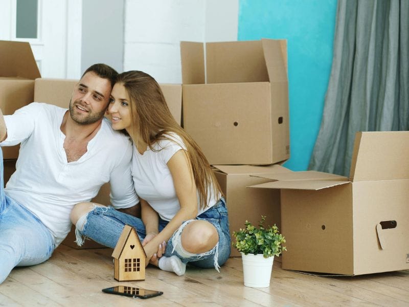 coppia tra scatoloni con modellino di casa