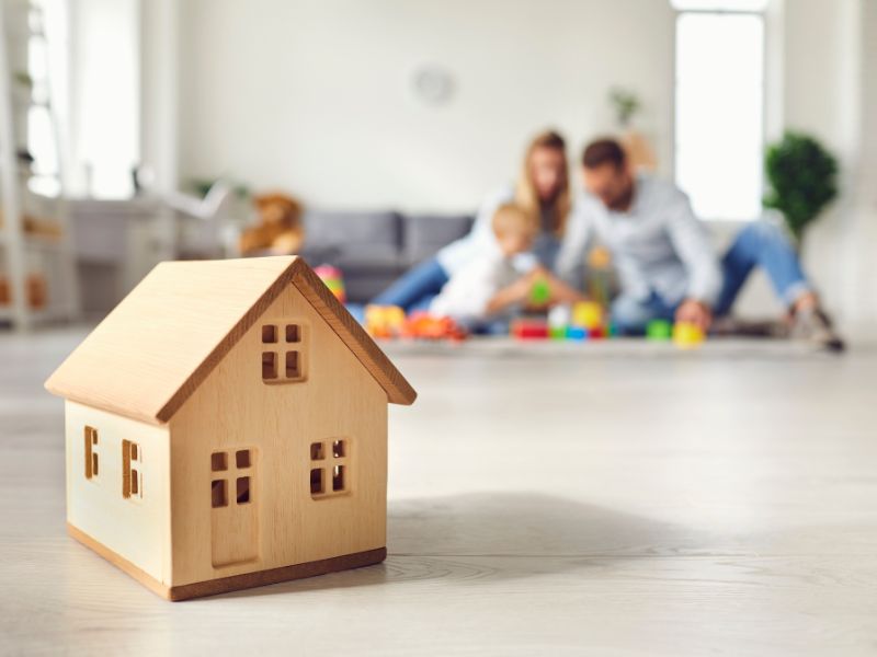 modellino di casa, sullo sfondo una famiglia