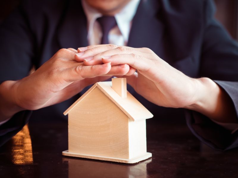 persona protegge con le mani una casa